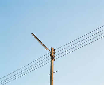 Low angle view of electricity pylon against clear sky