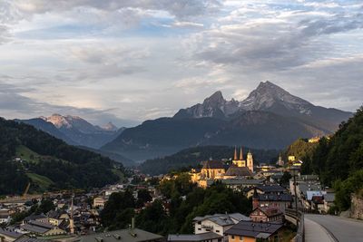 High angle view of town by mountain against cloudy sky