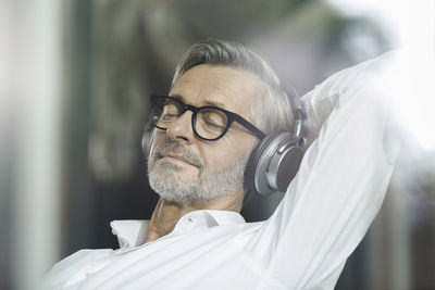 Portrait of man with eyes closed listening music with headphones