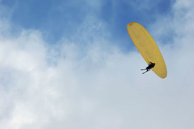 Low angle view of a yellow paraglide in cloudy blue sky with copy text space