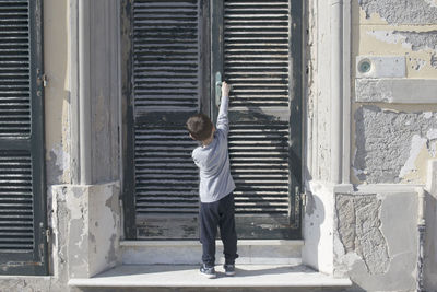 Rear view of boy standing against closed door