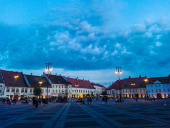 People on street amidst buildings at night