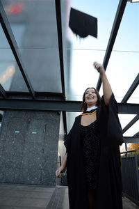 Smiling woman in graduation gown standing outdoors