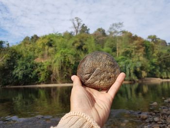 Close-up of hand holding pebble at lakeshore