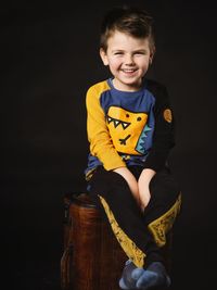 Portrait of cute girl sitting against black background