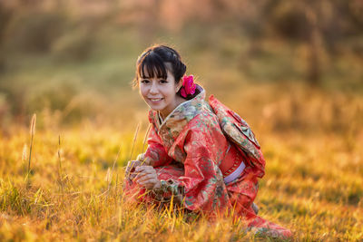 Portrait of smiling young woman sitting on field