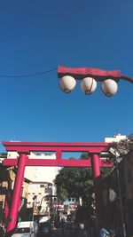 Low angle view of lanterns hanging against clear blue sky
