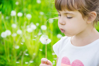 Close-up of girl blowing flowers