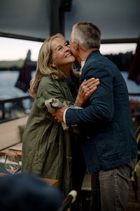 Smiling senior blond woman embracing man in restaurant