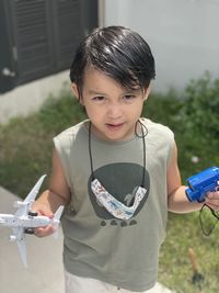 Boy holding toys standing outdoors