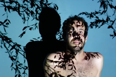 Portrait of shirtless man against sky