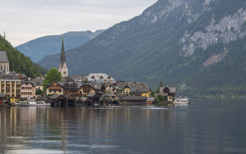 Houses by lake and buildings against sky