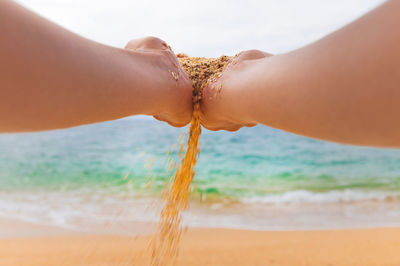 Hand releases the falling sand. fine sand flows through your fingers against the backdrop of the sea