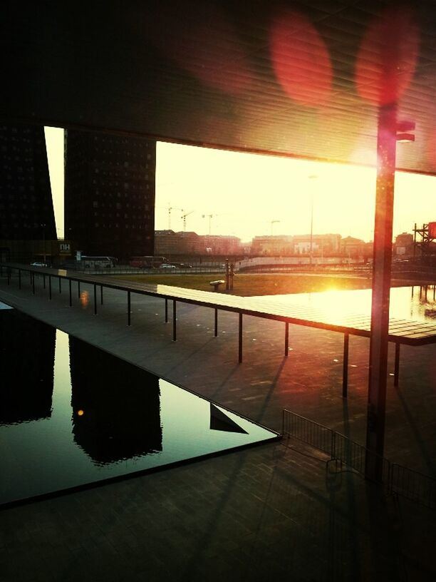 built structure, architecture, water, reflection, bridge - man made structure, connection, river, sunlight, sun, railing, building exterior, sunset, city, sky, sunbeam, bridge, no people, transportation, outdoors, waterfront