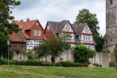 Houses by trees and buildings against sky