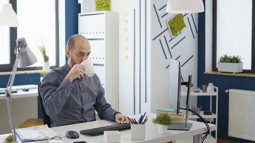 Businessman drinking coffee sitting at desk at office