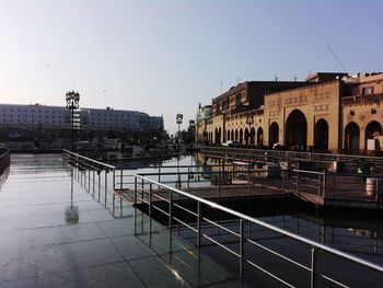 Bridge over river by buildings against clear sky