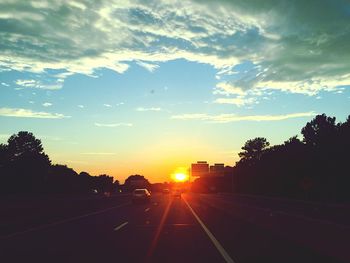 Cars on road against sky during sunset