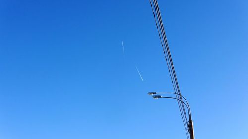 Low angle view of vapor trail against clear blue sky