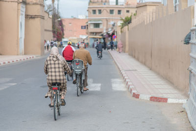 Rear view of people riding bicycle on road