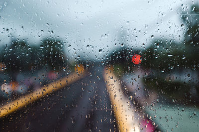 Road seen through wet glass window during rainy season