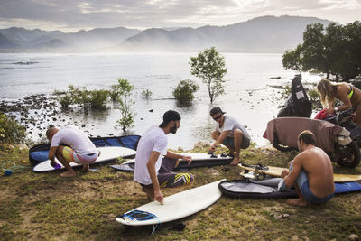 Male and female surfers preparing at lakeshore