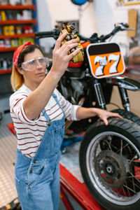 Mechanic woman checking motorbike caliper brake system on factory