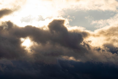 Low angle view of sunlight streaming through clouds