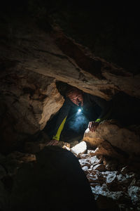 Man with flashlight exploring in cave