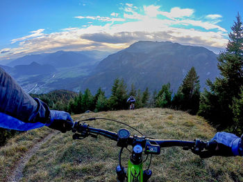 Man riding bicycle on mountain against sky