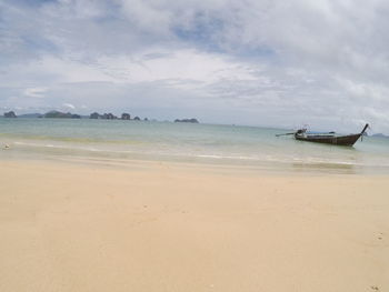 View of boat anchored at beach against cloudy sky