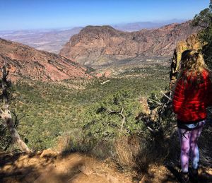 Rear view of woman standing on rocky mountain