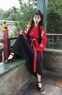 Full length portrait of young woman standing by railing