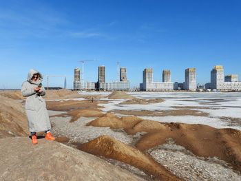 Rear view of woman standing at beach against sky