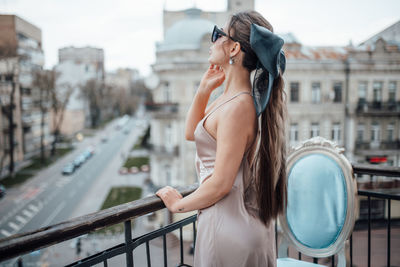 Young woman standing on railing in city