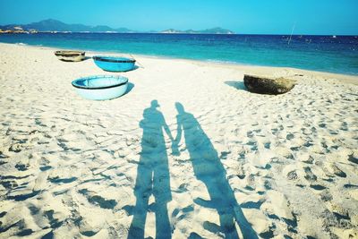 People on beach against clear blue sky