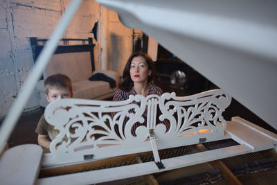 Portrait of mother with son by grand piano