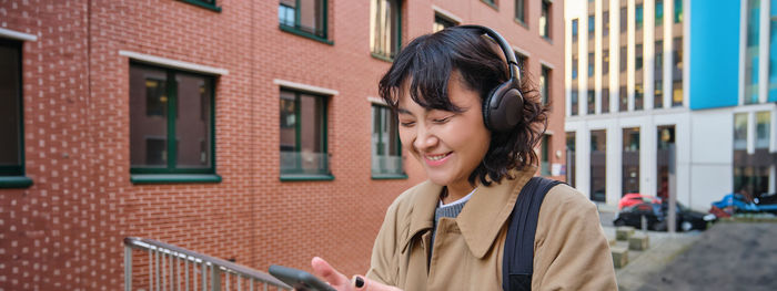 Side view of young woman standing against building