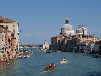 View of boats in canal amidst buildings in city