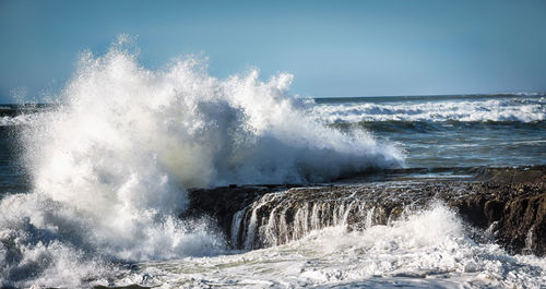 Waves splashing in sea against sky