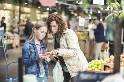 Mother and daughter using smart phone in organic grocery store