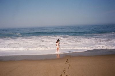 Rear view of woman standing at beach
