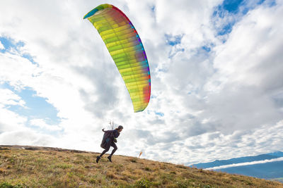 Man paragliding over field against sky