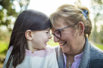 Grandma smiling at granddaughter in outdoor setting.