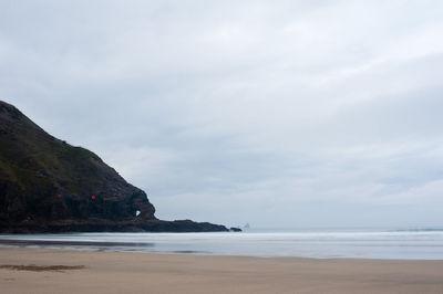 Rock formation in sea against cloudy sky