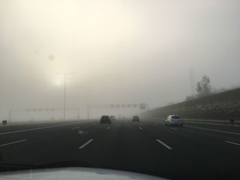 Cars on road against sky seen through car windshield