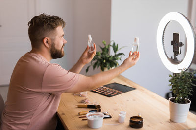 Side view of man using mobile phone while sitting at home