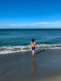 Rear view of woman on beach against sky