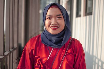 Portrait of smiling young woman wearing hijab while standing at home