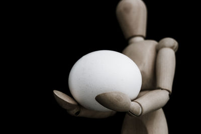 Close-up of hand holding apple against black background